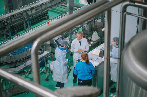Asian Chinese factory inspector meeting production line worker discussion on checking mineral water quality and production progress at drinking water factory production line in daily routine inspector de fábrica chino asiático se reúne con el trabajador de la línea de producción para verificar la calidad del agua mineral y el progreso de la producción en la línea de producción de la fábrica de agua potable en la rutina diaria