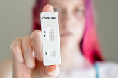 Teenage girl holding Covid-19 rapid antigen test cassette with positive result of rapid diagnostic test