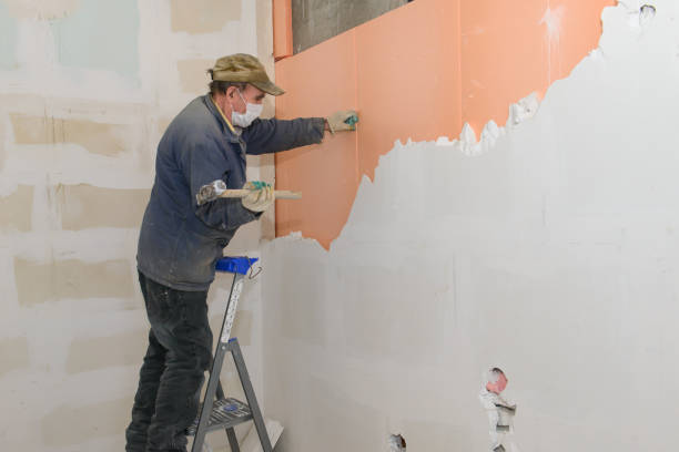 istock A worker on a stepladder breaks a wall of plaster blocks 1367661004