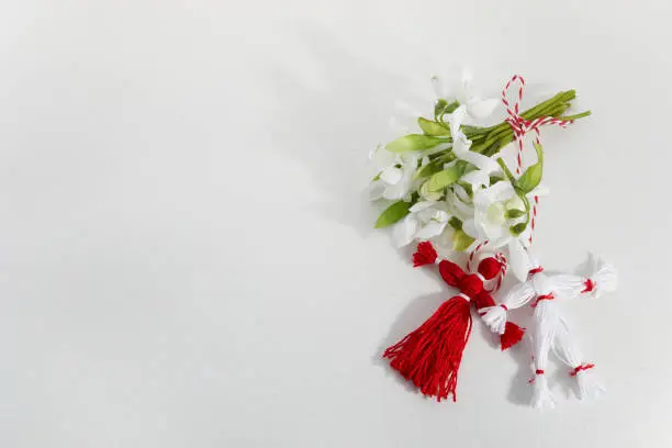 Bouquet of snowdrops and Martisor red and white dalls on shining white background. Holiday Martisor and Baba Marta.