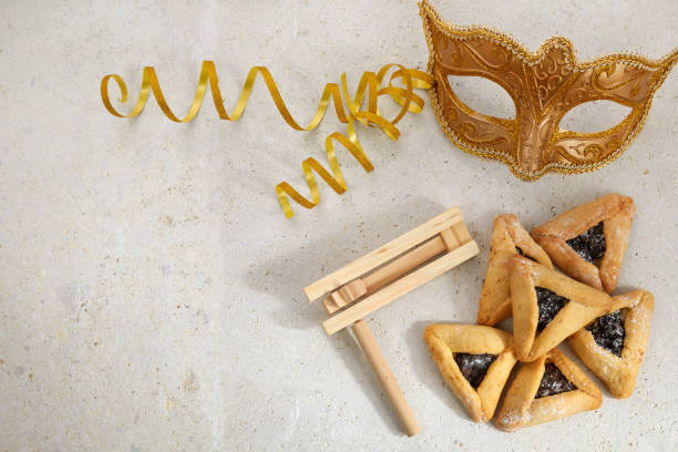 fond de fête juive de pourim avec des biscuits hamantaschen ou hamans ears, masque de carnaval et bruiteur - pourim photos et images de collection