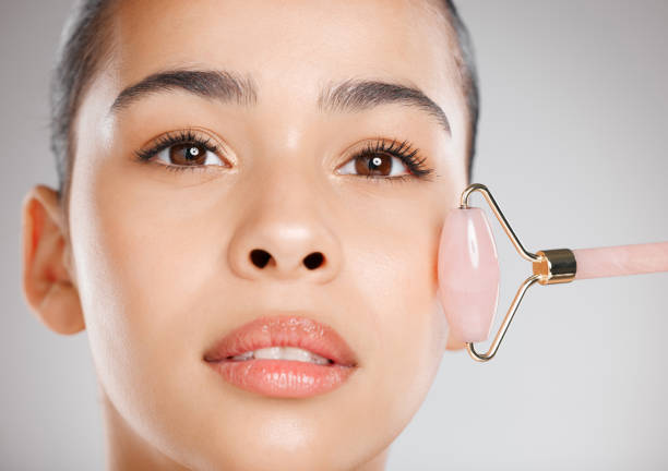 istock Studio shot of an attractive young woman using a jade roller on her face against a grey background 1367667983