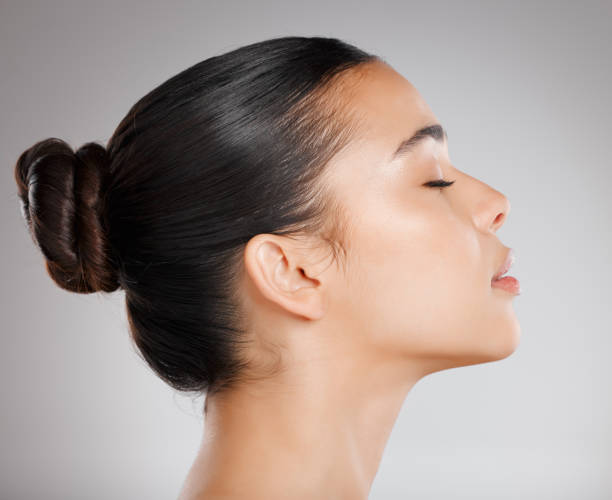 studioaufnahme einer attraktiven jungen frau, die vor grauem hintergrund posiert - haarknoten stock-fotos und bilder