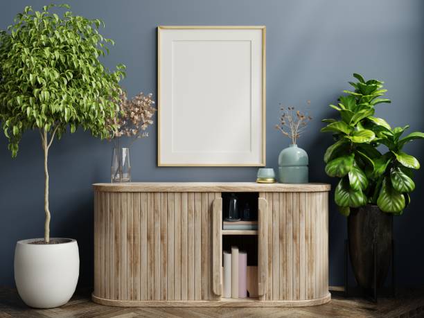 istock Poster frame mockup with wooden frame and cabinet on blue wall background. 1367669003