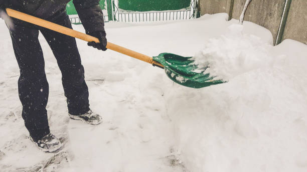 istock Man with green snow shovel cleans pavement in winter yard 1367672085