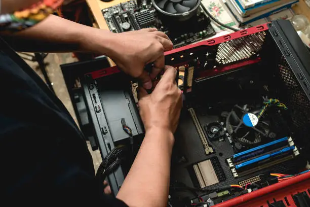 Photo of A computer technician assembles a desktop computer with new parts. Upgrading or replacing PC parts.