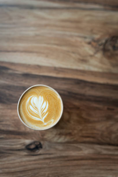 Cappuccino coffee with beautiful pattern on foam in eco craft glass on table favorite coffee cup concept. View from above