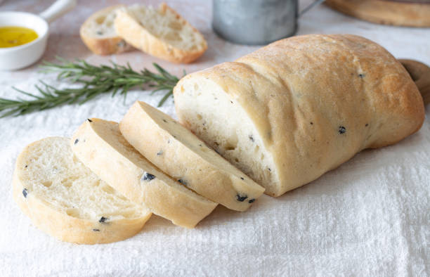 ciabatta di grano a fette con olive su un asciugamano bianco. pane di grano fatto in casa - ciabatta foto e immagini stock