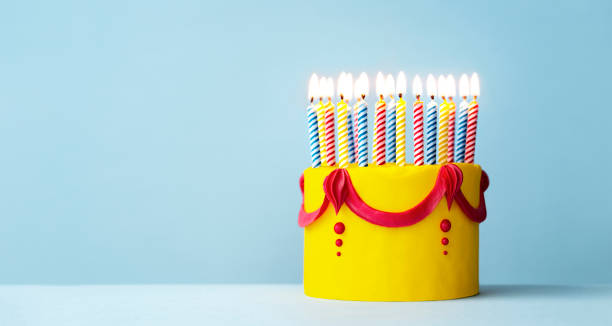 Colorful yellow birthday cake with candles stock photo