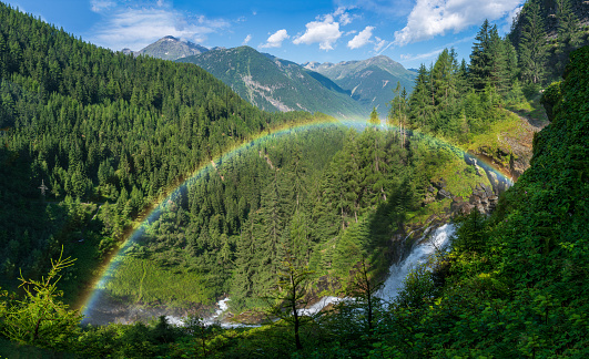 Colorful rainbow from famous natural landmark waterfall Stuibenfall in beautiful forest mountain valley in Ötztal, Austria