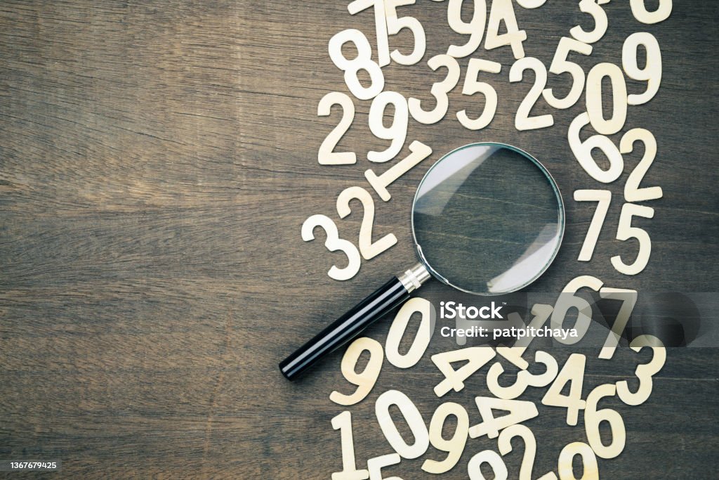 Magnifying glass in scattered numbers Magnifying glass in scattered numbers on wood background, calculation, mathematics concept Number Stock Photo