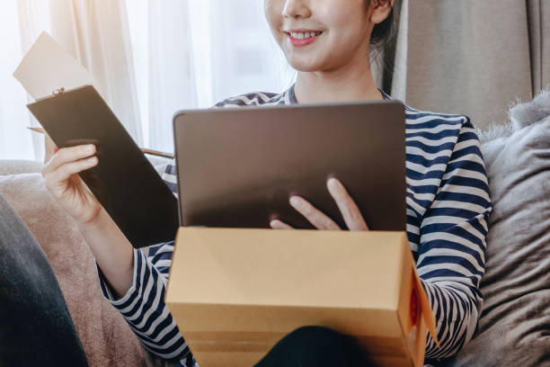 istock Online merchandising business idea, beautiful girl using tablet computer to check orders to deliver parcels to customers according to orders received from customers. 1367679611