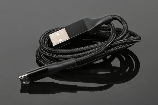 istock Black USB cable for charging a smartphone on black acrylic background. 1367682350