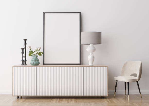 istock Empty vertical picture frame on white wall in modern living room. Mock up interior in contemporary style. Free space for picture, poster. Console, armchair, lamp, flowers. 3D rendering. 1367684553