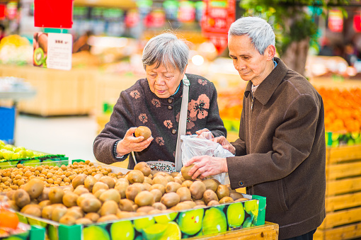 Senior Man and Woman Shopping Fruit. A  senior couple, 80 years old, is selecting fruits in a supermarket.\