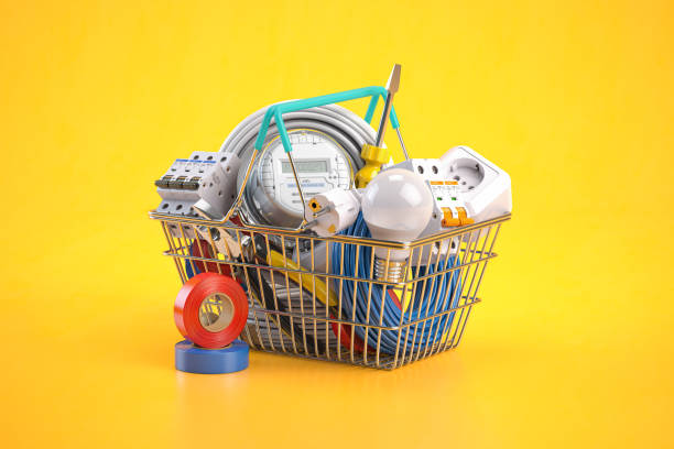 Shopping cart full of electrical components and equipment on yellow background. stock photo