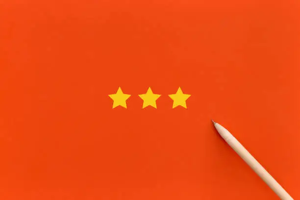 Photo of Three 3 stars, best excellent services rating on red background.