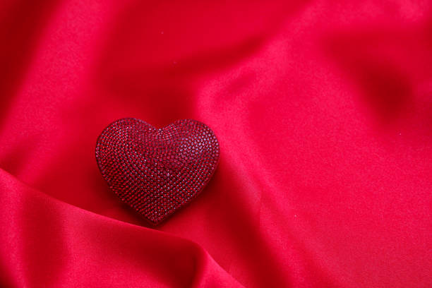 istock Red color ruby heart jewel on empty silk background. Valentine day, love celebration. 1367694510
