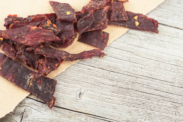 istock Spiced beef jerky on a wooden board. Sliced beef jerky. Dried meat. 1367695922