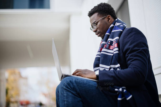istock Young Modern businessman sitting on steps outdoors using laptop 1367696853