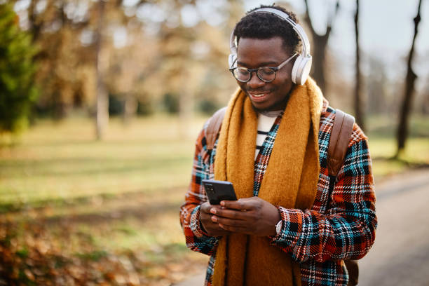 istock The young man walks through the park while sending messages on his smartphone 1367698289