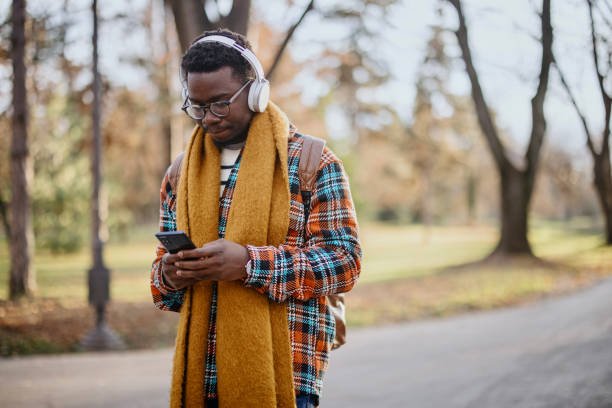 istock The young man walks through the park while sending messages on his smartphone 1367698789