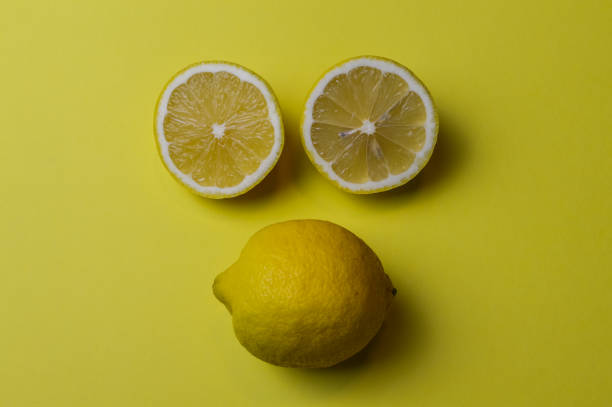 istock lemon face, two half lemons and a whole lemon which from the arrangement resemble a face, on a background of yellow paper 1367699339