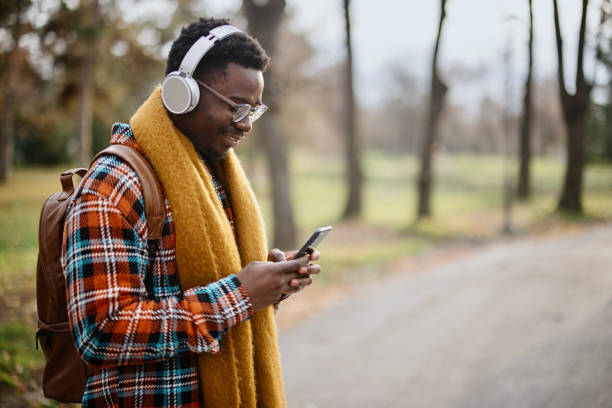 istock The young man walks through the park while sending messages on his smartphone 1367699672