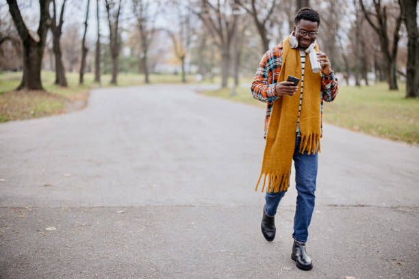 istock The young man drinks water from a reusable bottle as he walks through the park and types a message 1367699749