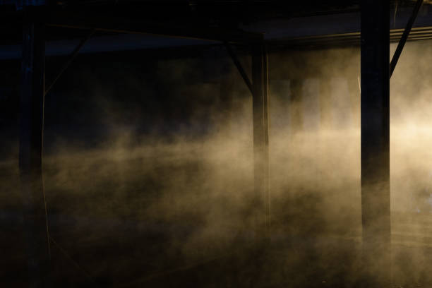 Bridge support beams in mist covered water at sunrise