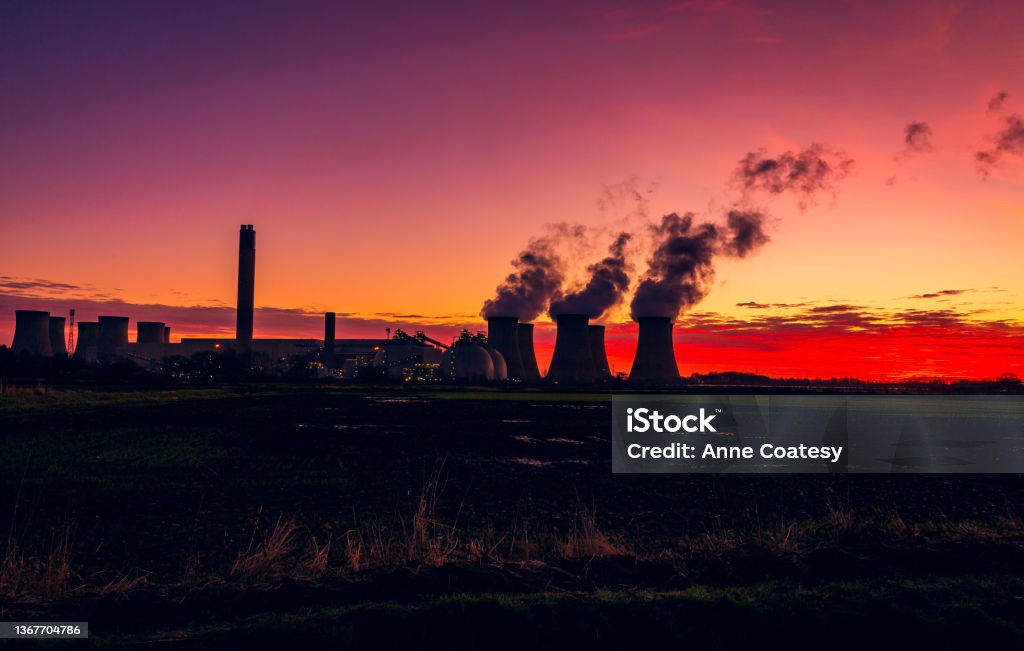 Silhouette of a power station against a stunning and colourful winter sunrise near Drax in North Yorkshire, UK with plumes of water vapour rising from the cooling towers. Silhouette of a power station against a winter sunrise near Drax in North Yorkshire, UK, with plumes of water vapour rising from the cooling towers.  Horizontal.  Copy space Carbon Capture Stock Photo