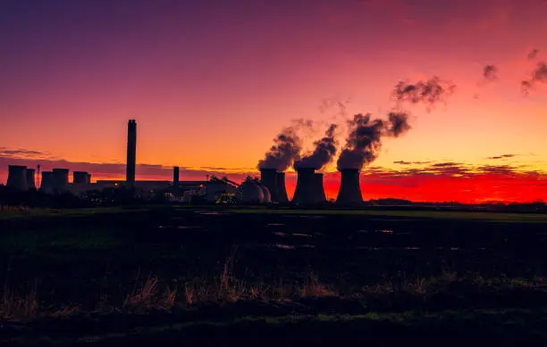 Photo of Silhouette of a power station against a stunning and colourful winter sunrise near Drax in North Yorkshire, UK with plumes of water vapour rising from the cooling towers.