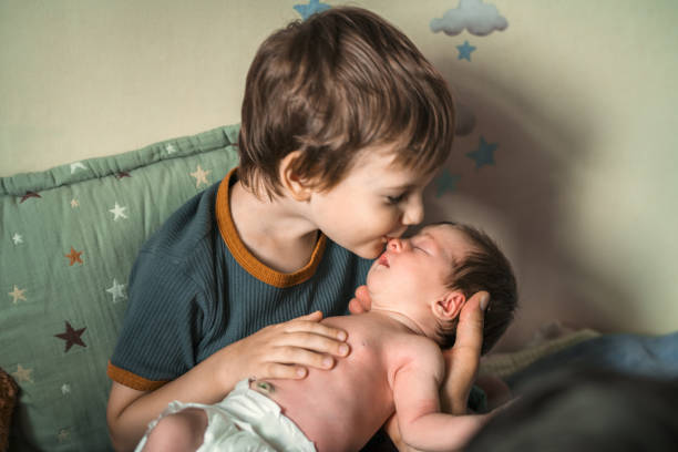 Little boy kissing his newborn sister stock photo