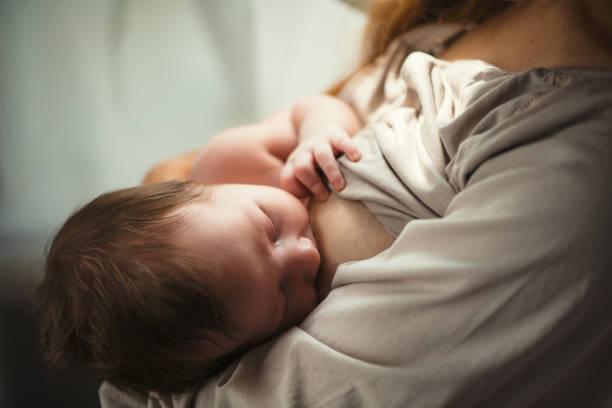 Mother breastfeeding her newborn baby girl stock photo