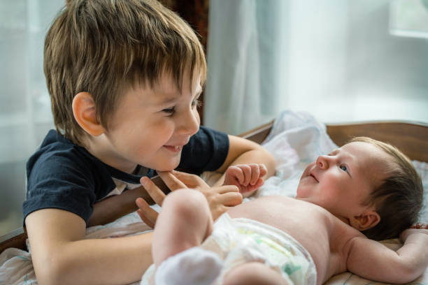 Little boy meeting his cute baby sister stock photo