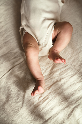 Close up crop legs of newborn baby wrapped in warm knitted blanket