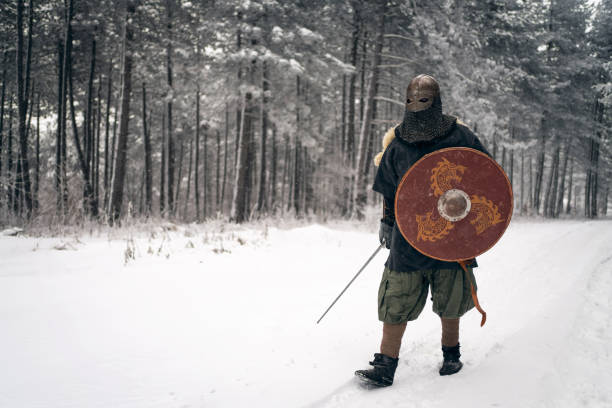 Mid-adult Caucasian man, wearing the warrior costume, shield and spear, at nature during winter