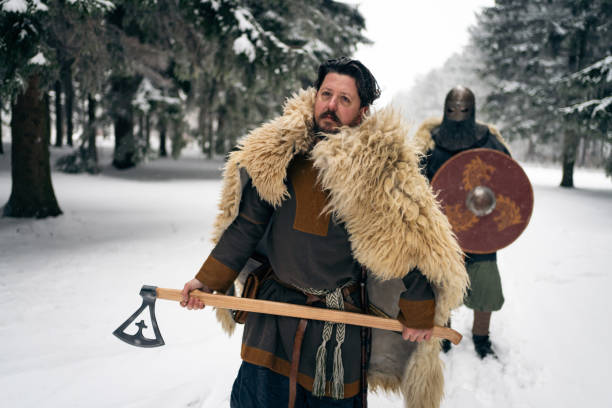 Medieval warrior walking in front of the unrecognizable knight, during their walk in the snowy forest