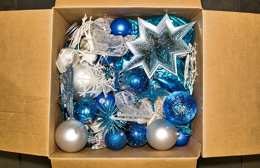 Assorted Christmas ornament decorations stored in an open cardboard box from directly above.