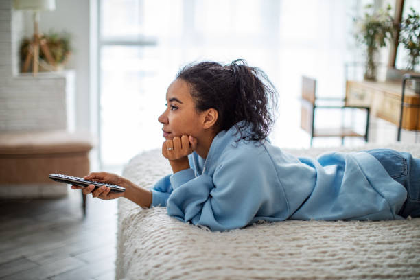 Young African woman watching TV at home stock photo