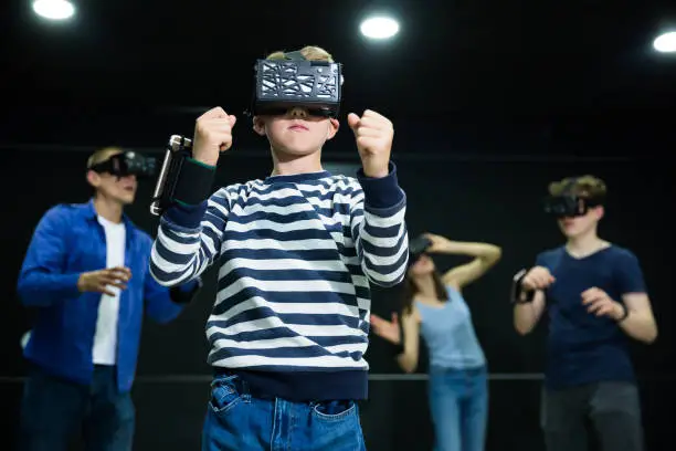 Photo of Emotional tween boy playing vr game with family