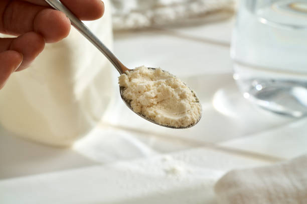 istock Hand holding a spoon with whey protein powder above white background 1367710650
