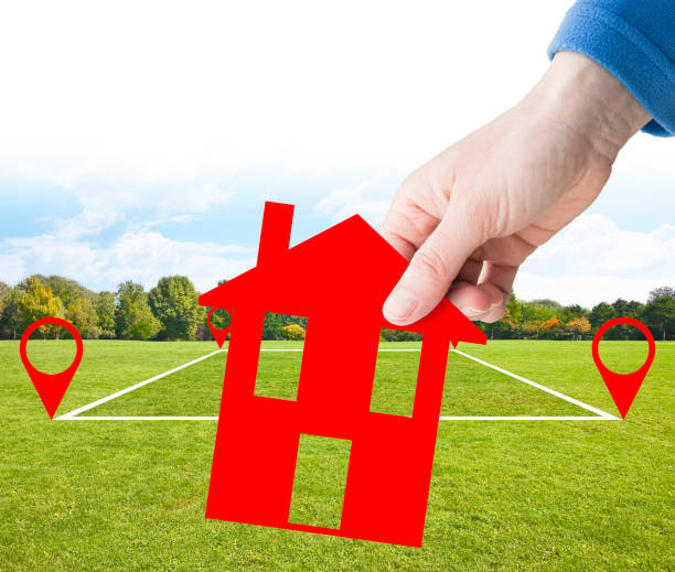 istock Land plot management - real estate concept with a vacant land parcel available for building construction - housing concept with hand holding a little red house in a residential area for sale 1367711576