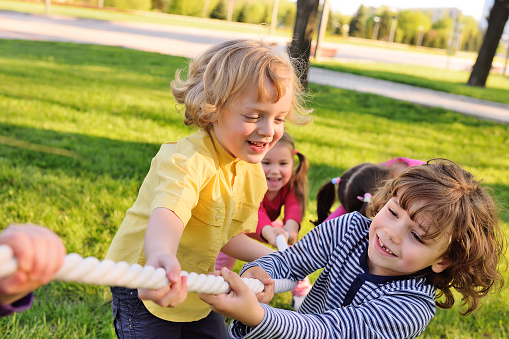 Children play tug of war in the park. Children's Day, June 1, friendship, childhood, vacation, camp