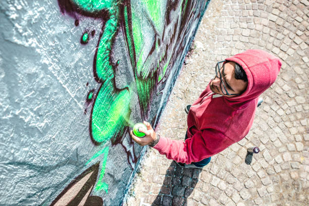 draufsicht auf straßenkünstler, die graffiti an die generische wand malen - modernes kunstkonzept mit urbanem mann, der live-wandmalereien mit grünem aerosol-farbspray durchführt und vorbereitet - heller lebendiger filter - straßenmaler stock-fotos und bilder