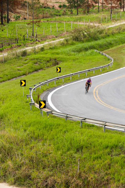 cycliste solitaire faisant une courbe sur l’autoroute mise à l’écart par la végétation verte - sao paulo sao paulo state people brazil photos et images de collection