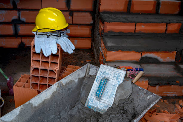 Gloves, helmet and goggles on pile of bricks, with wheelbarrow at the front, on construction site. Sao Paulo city, Brazil.