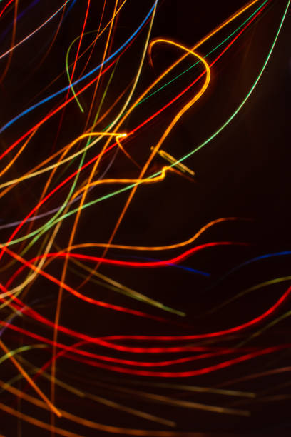 drawing with light. abstract multicolored rays on a black background. curved wave lines. - blue streak lights imagens e fotografias de stock