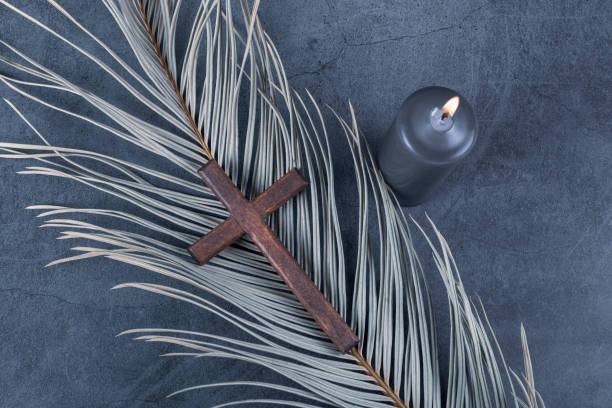 Catholic Cross with palm leaf and burning candle. Ash Wednesday, Lent season, Holy Week, Good Friday and Palm Sunday concept. Catholic Cross with palm leaf and burning candle. Ash Wednesday, Lent season, Holy Week, Good Friday and Palm Sunday concept. Copy space. church like a holy light from god stock pictures, royalty-free photos & images