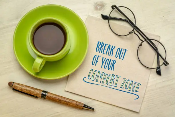 break out of your comfort zone concept - motivational handwriting on a napkin with a cup of coffee, challenge, motivation and personal development